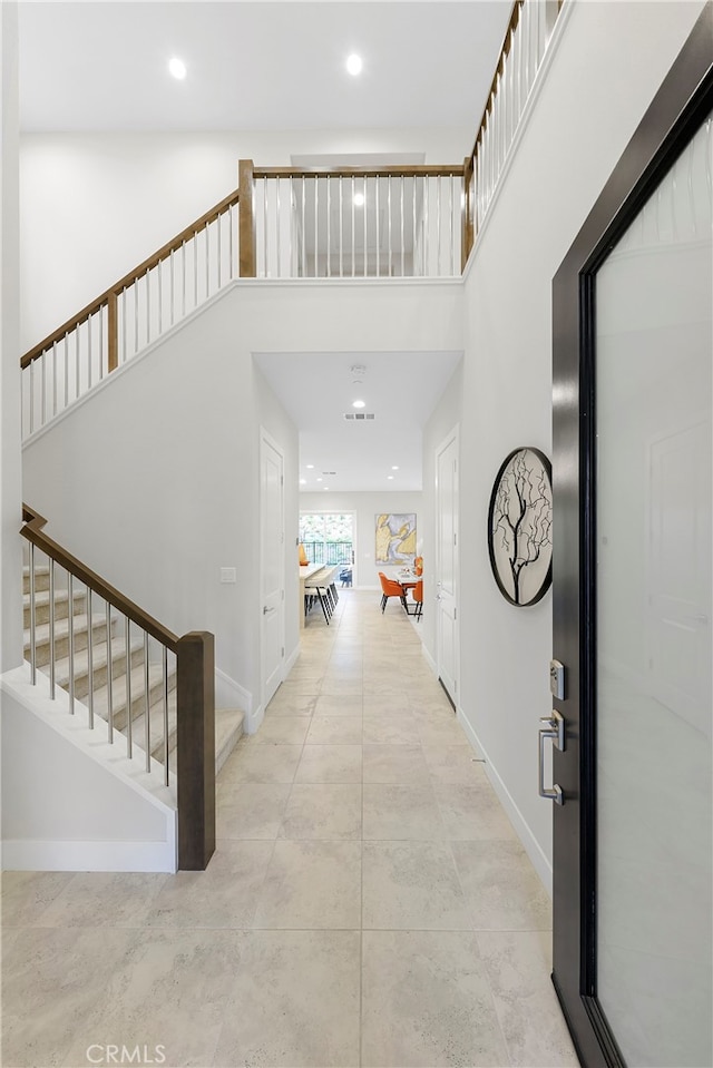 entryway featuring light tile floors and a towering ceiling