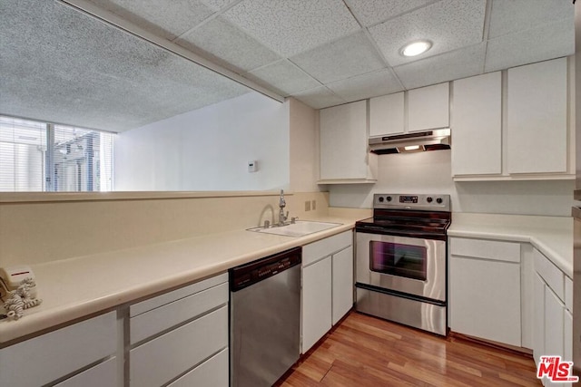 kitchen with appliances with stainless steel finishes, white cabinets, sink, and light hardwood / wood-style floors