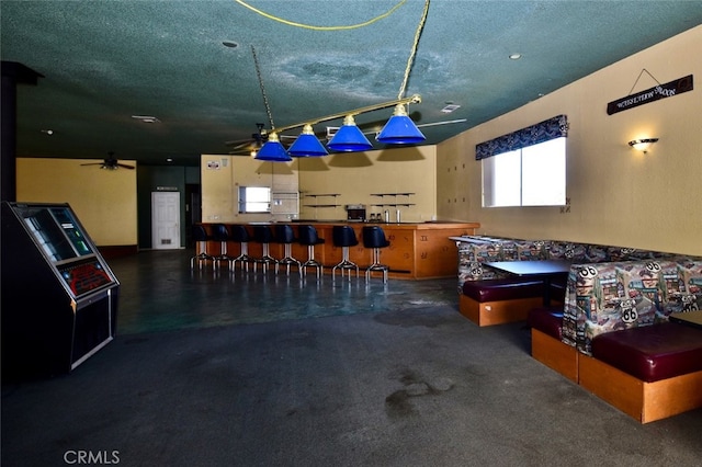 interior space featuring a textured ceiling, indoor bar, and ceiling fan