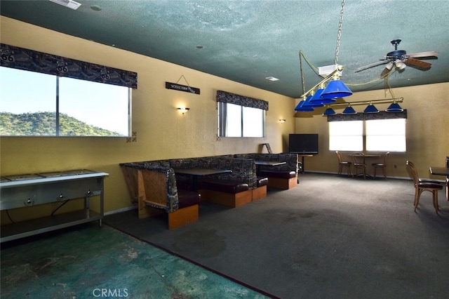 recreation room featuring carpet floors, a textured ceiling, and ceiling fan