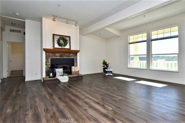 unfurnished living room featuring beam ceiling, rail lighting, and dark hardwood / wood-style floors