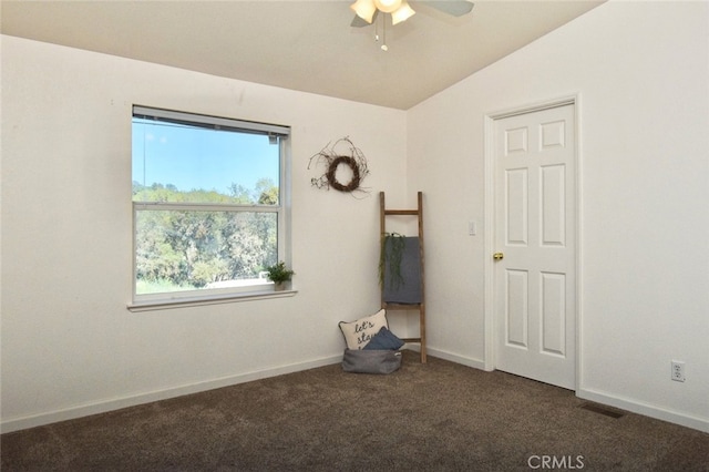 spare room featuring vaulted ceiling, dark carpet, and ceiling fan