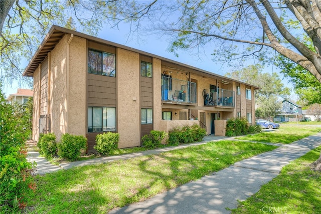 view of front of property featuring a balcony and a front yard