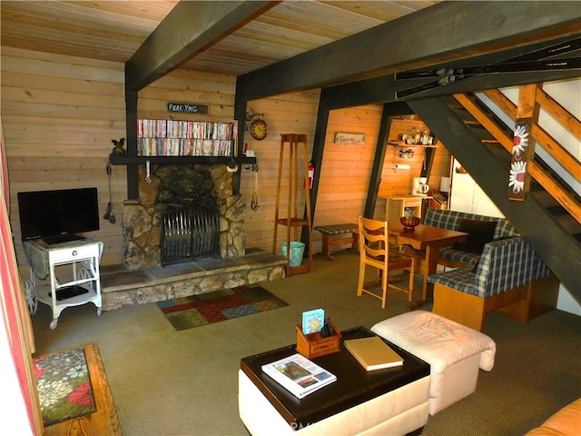 carpeted living room with wooden walls, beam ceiling, ceiling fan, and a fireplace