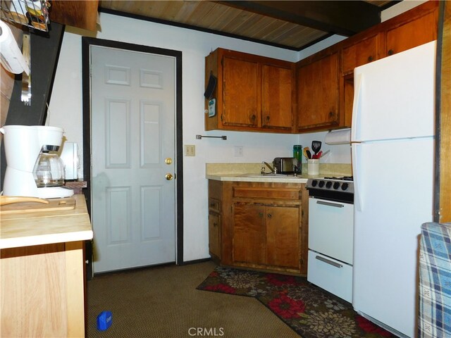 kitchen with white appliances, dark colored carpet, and sink