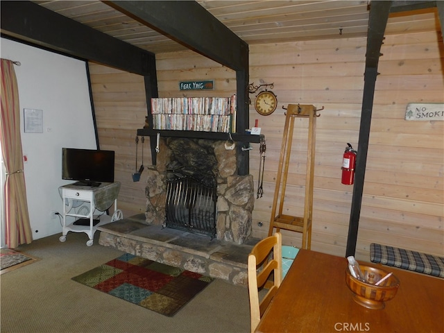 carpeted living room with beam ceiling, a fireplace, and wood walls