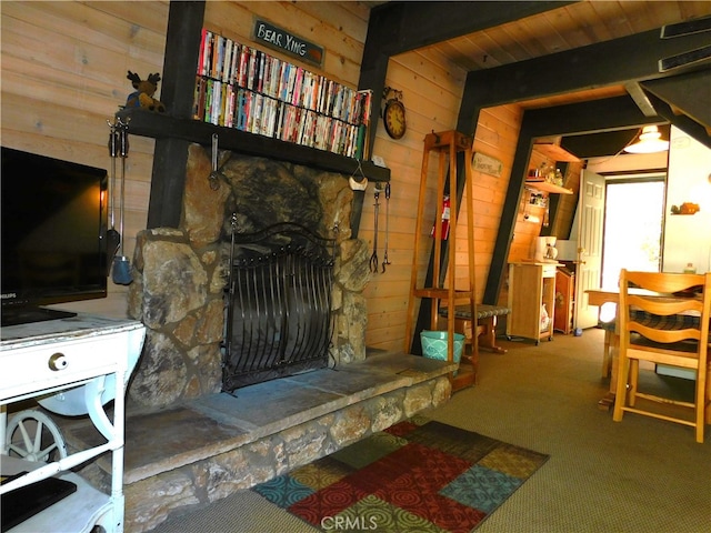 living room featuring carpet flooring, wooden ceiling, wood walls, and a stone fireplace