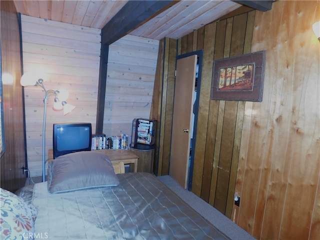 bedroom featuring beam ceiling and wooden walls