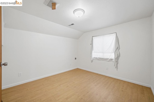 additional living space featuring light hardwood / wood-style flooring and vaulted ceiling