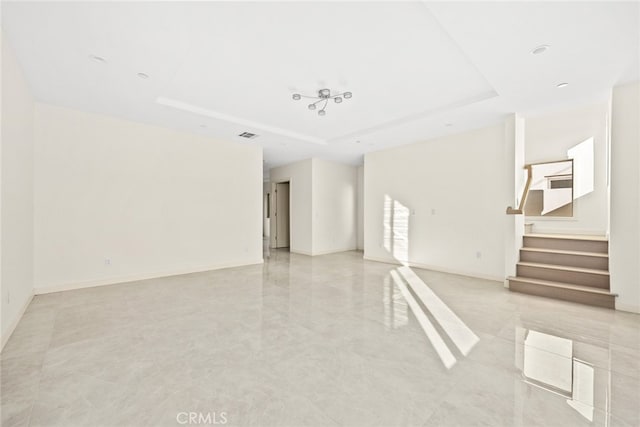 tiled spare room featuring a tray ceiling