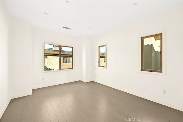 unfurnished room with dark hardwood / wood-style floors and a healthy amount of sunlight