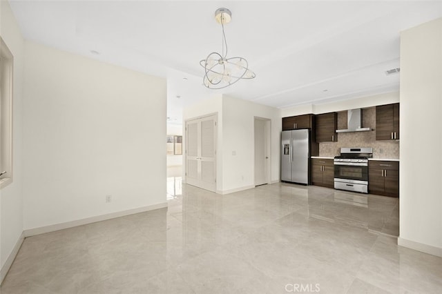 kitchen featuring gas stove, backsplash, wall chimney exhaust hood, an inviting chandelier, and stainless steel refrigerator with ice dispenser