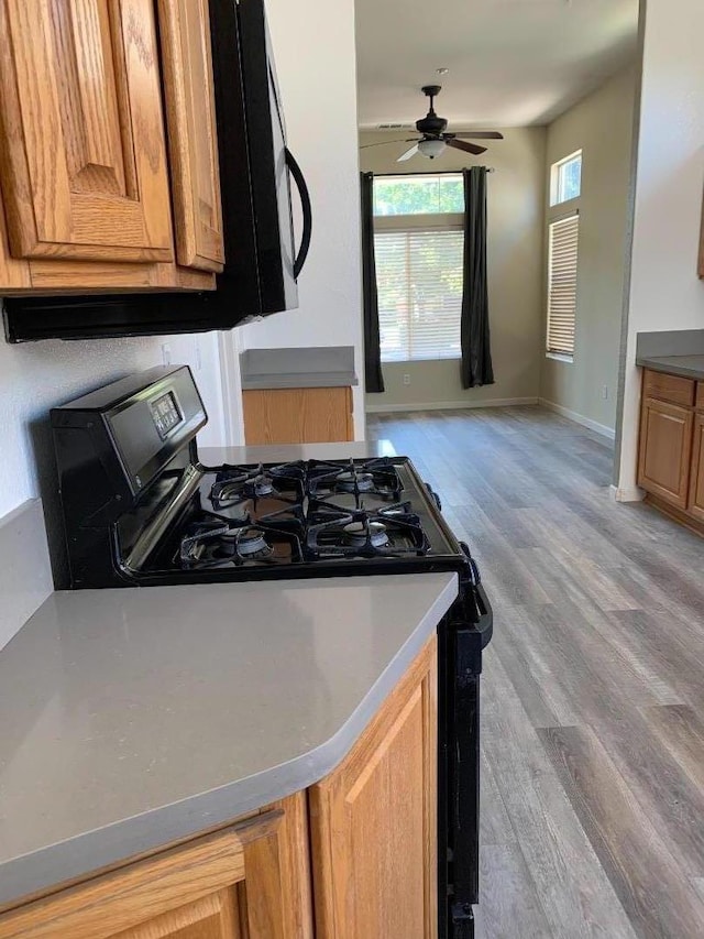 kitchen with ceiling fan, light hardwood / wood-style floors, and gas stove