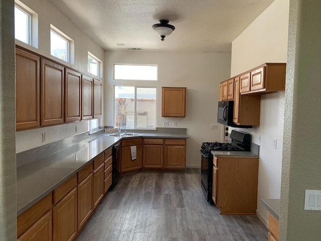 kitchen featuring a textured ceiling, sink, hardwood / wood-style floors, and black appliances