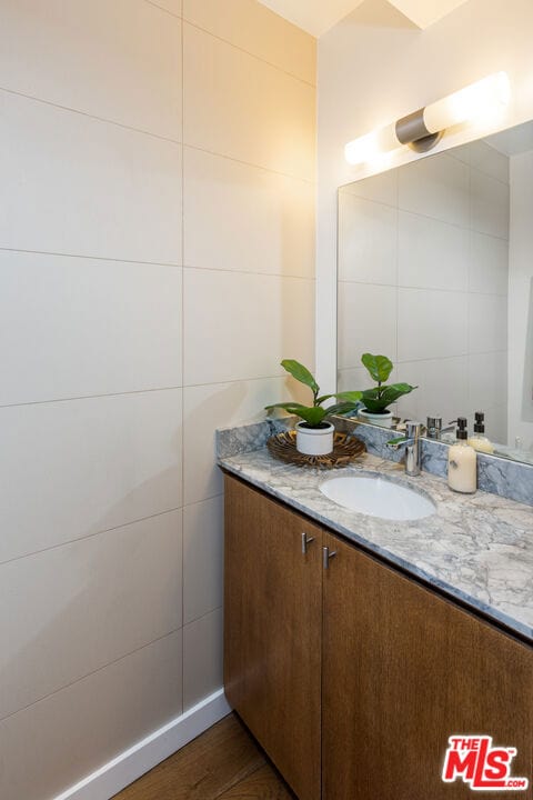 bathroom with hardwood / wood-style flooring, tile walls, and vanity