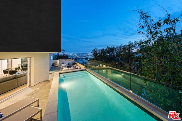 pool at dusk featuring a patio