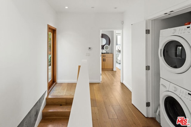 washroom with light hardwood / wood-style flooring and stacked washing maching and dryer