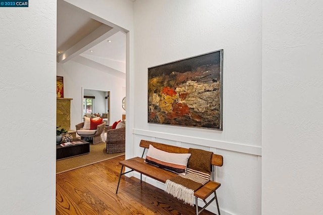 corridor with light hardwood / wood-style floors and vaulted ceiling with beams