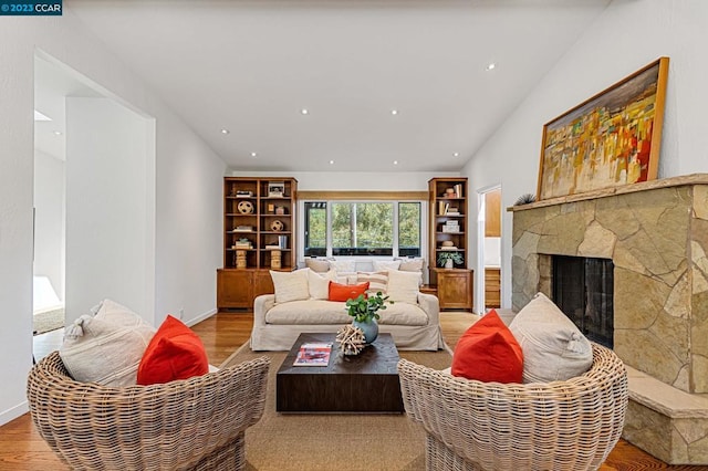 living room with lofted ceiling, light wood-type flooring, and a fireplace