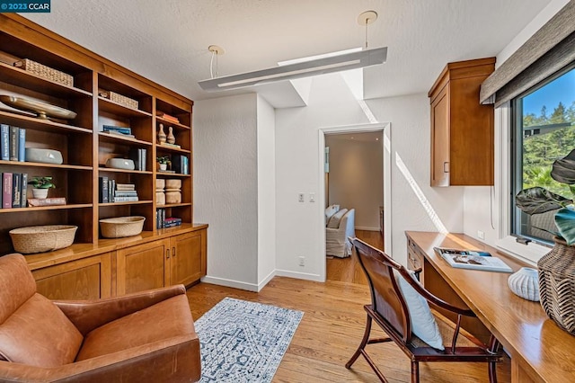 home office with light hardwood / wood-style flooring and a textured ceiling