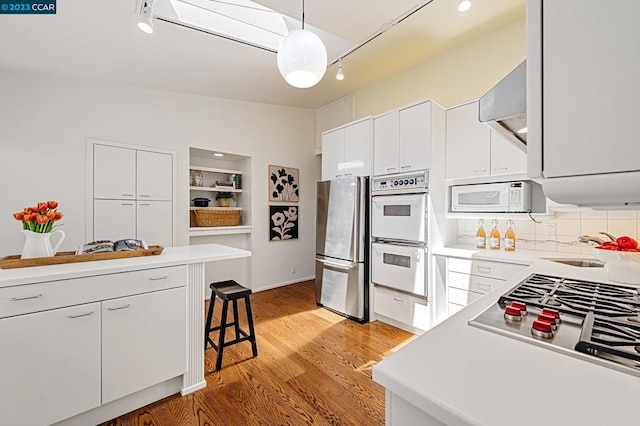 kitchen with white cabinetry, a kitchen breakfast bar, appliances with stainless steel finishes, light hardwood / wood-style floors, and wall chimney exhaust hood