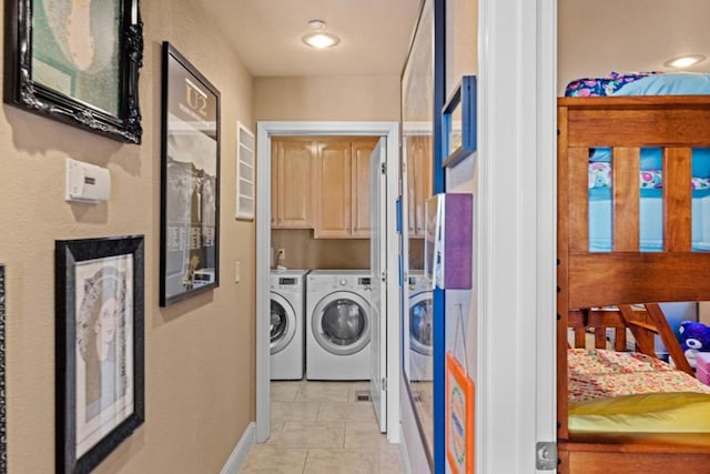 laundry area featuring cabinets, light tile patterned flooring, and independent washer and dryer