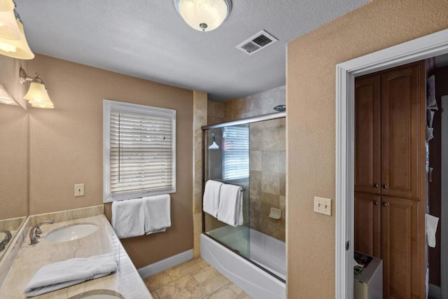 bathroom featuring dual vanity, a textured ceiling, shower / bath combination with glass door, and tile patterned flooring