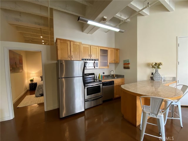 kitchen featuring sink, kitchen peninsula, stainless steel appliances, a high ceiling, and a breakfast bar