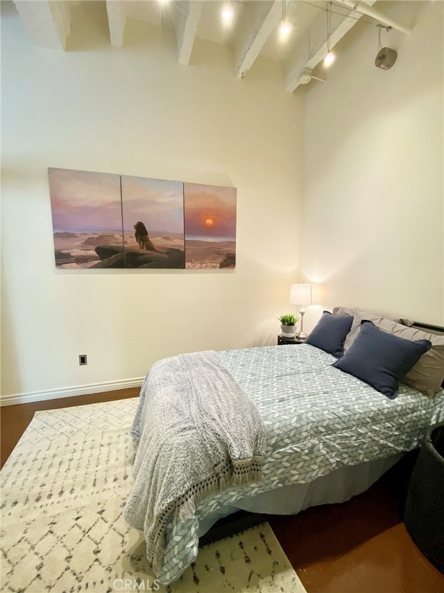 bedroom with hardwood / wood-style floors and beam ceiling