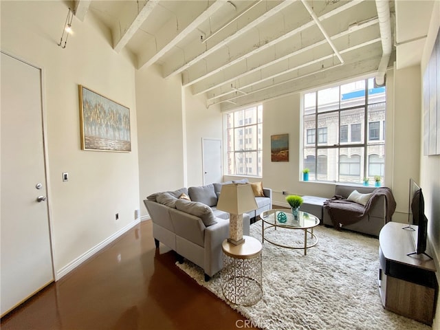 living room featuring concrete flooring, beamed ceiling, and plenty of natural light