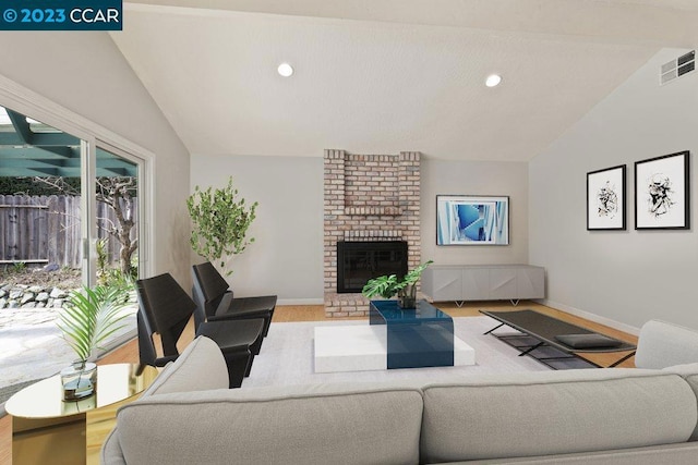 living room featuring brick wall, a brick fireplace, vaulted ceiling, and light hardwood / wood-style flooring