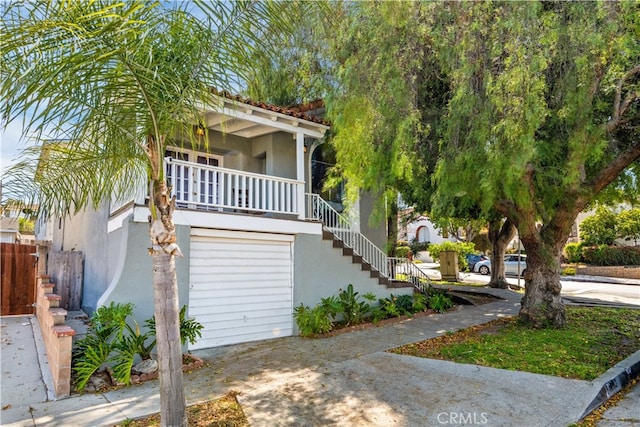 view of front of home with stairs, concrete driveway, and stucco siding