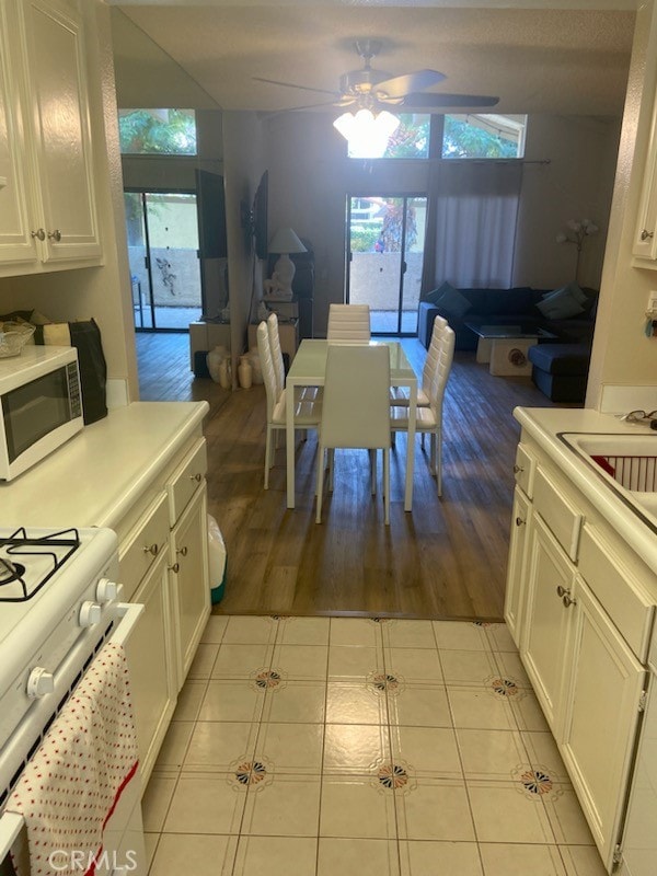 kitchen featuring sink, white cabinets, light tile patterned floors, ceiling fan, and white appliances