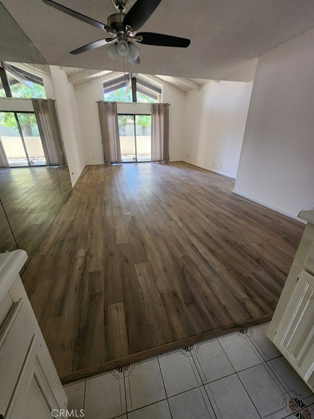 spare room featuring a textured ceiling, vaulted ceiling, ceiling fan, and light wood-type flooring