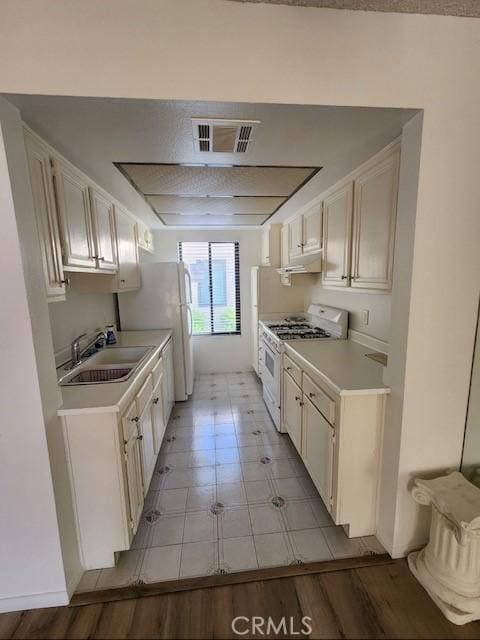 kitchen with white range with gas cooktop, sink, light hardwood / wood-style flooring, and white cabinets