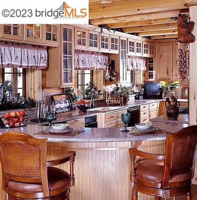 kitchen featuring black dishwasher, beam ceiling, and sink