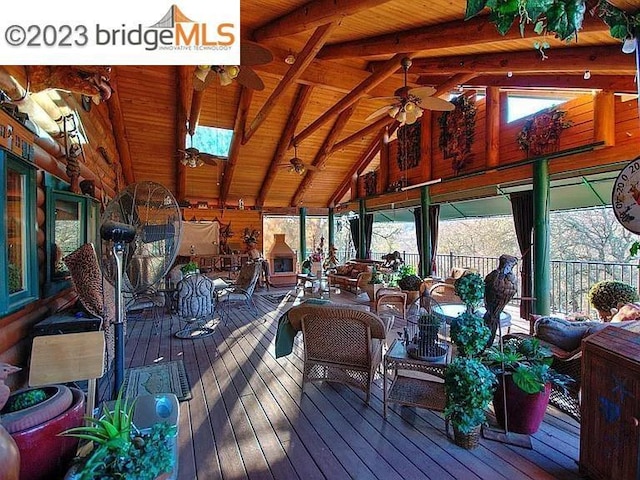 sunroom / solarium with vaulted ceiling with skylight, ceiling fan, and a wealth of natural light