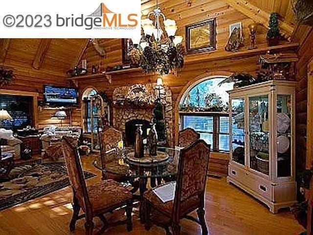 dining space with beam ceiling, wood-type flooring, wooden ceiling, a chandelier, and wood walls