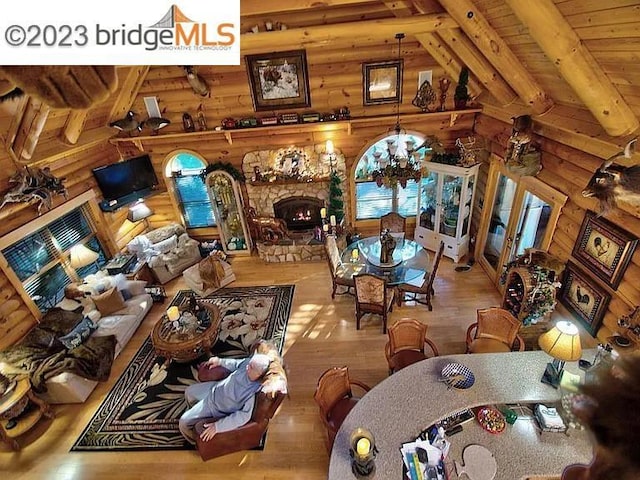 dining area featuring wooden ceiling, wooden walls, hardwood / wood-style flooring, vaulted ceiling with beams, and a fireplace