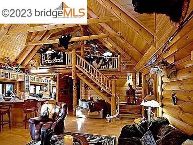 living room featuring hardwood / wood-style flooring, lofted ceiling with beams, wooden ceiling, and log walls