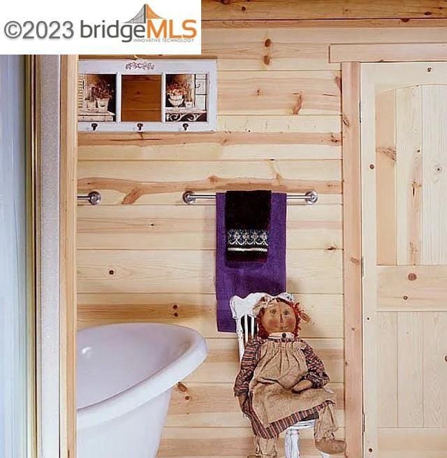 bathroom featuring a tub to relax in and wooden walls