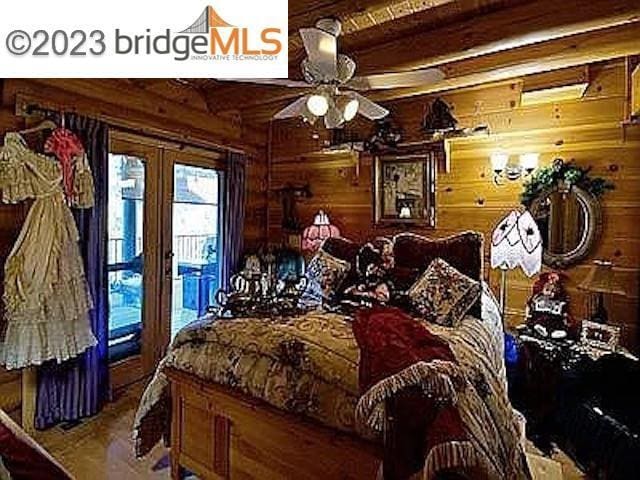 bedroom with beamed ceiling, ceiling fan, and wooden walls