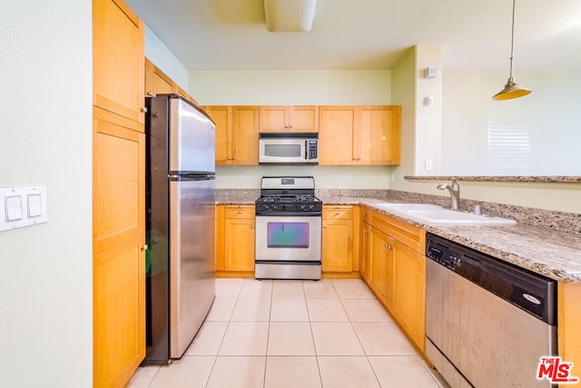 kitchen with stainless steel appliances, sink, light stone countertops, decorative light fixtures, and light tile patterned floors