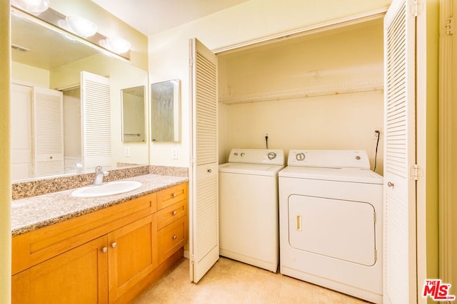 laundry area featuring light tile patterned floors, sink, and separate washer and dryer