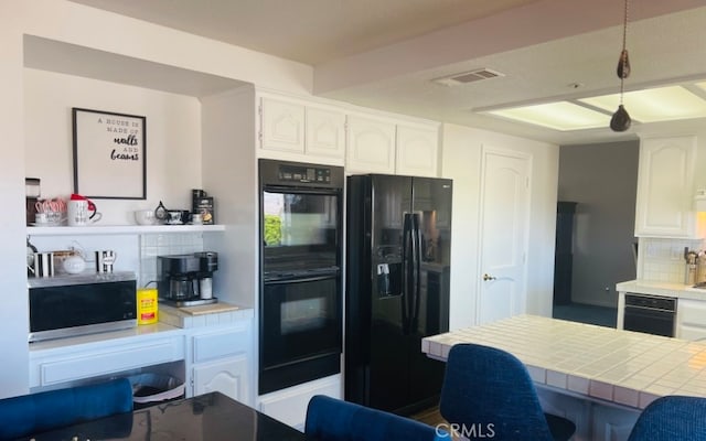 kitchen with black appliances, tasteful backsplash, white cabinets, tile counters, and decorative light fixtures