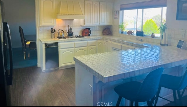 kitchen with premium range hood, kitchen peninsula, dark wood-type flooring, tile countertops, and white gas stovetop