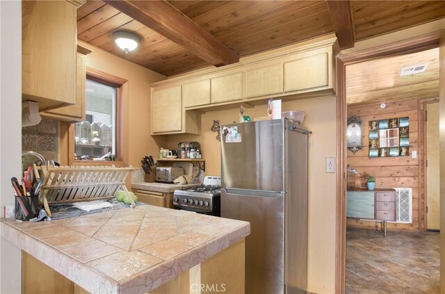 kitchen with wooden walls, stainless steel appliances, wooden ceiling, tile countertops, and beam ceiling