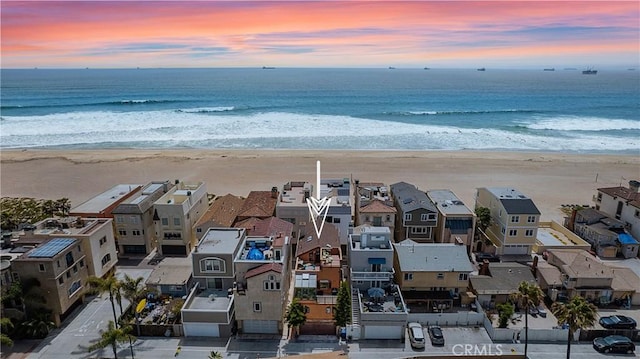 aerial view at dusk with a view of the beach and a water view