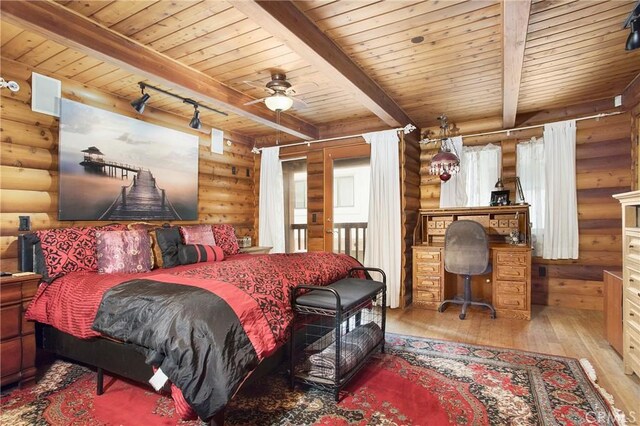 bedroom with track lighting, rustic walls, light wood-type flooring, and beamed ceiling