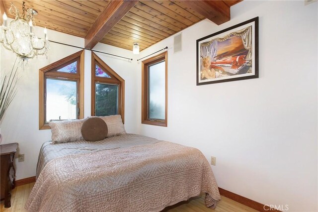 bedroom with an inviting chandelier, beam ceiling, and light hardwood / wood-style floors